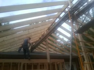 Rafters going up over a new addition with a worker on the wall in Dungannon