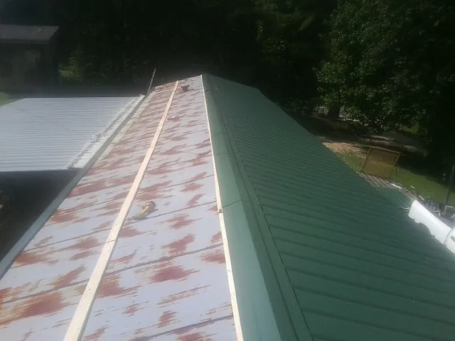 Old rusted panels beside newly installed green metal roofing — Wind Damage Roof Repair by Roofing Brothers in Dungannon