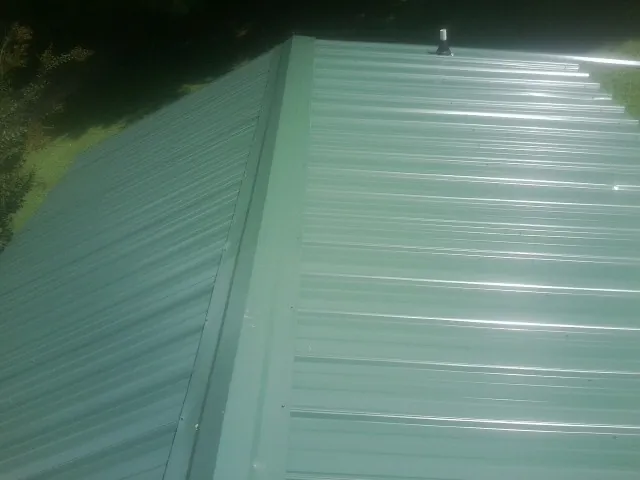 New green metal panels meeting at the ridge of a roof — Flat Roof Repair work by our crew in Dungannon