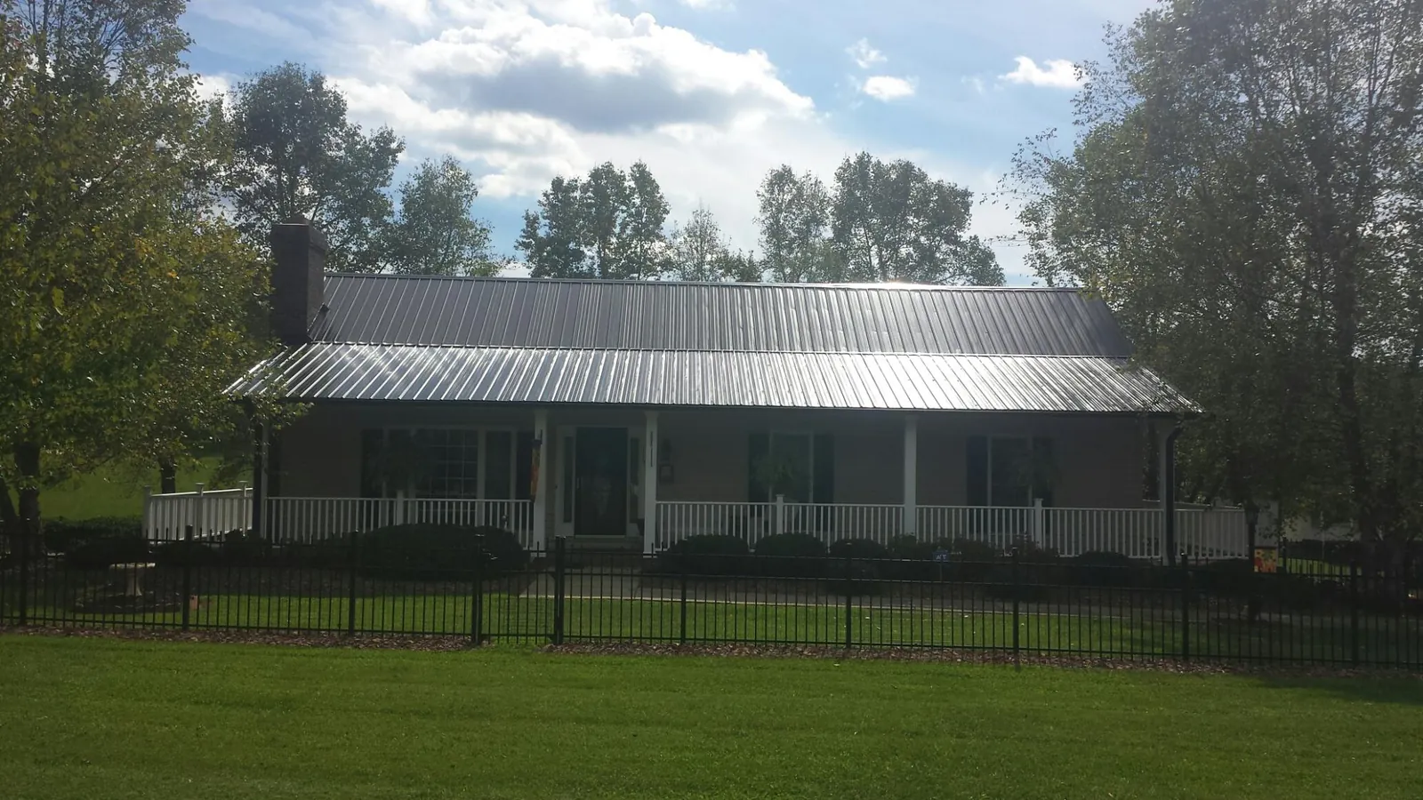 Gray metal roof on a brick ranch with a full width front porch — Gutter Guard Installation work by our crew in Dungannon