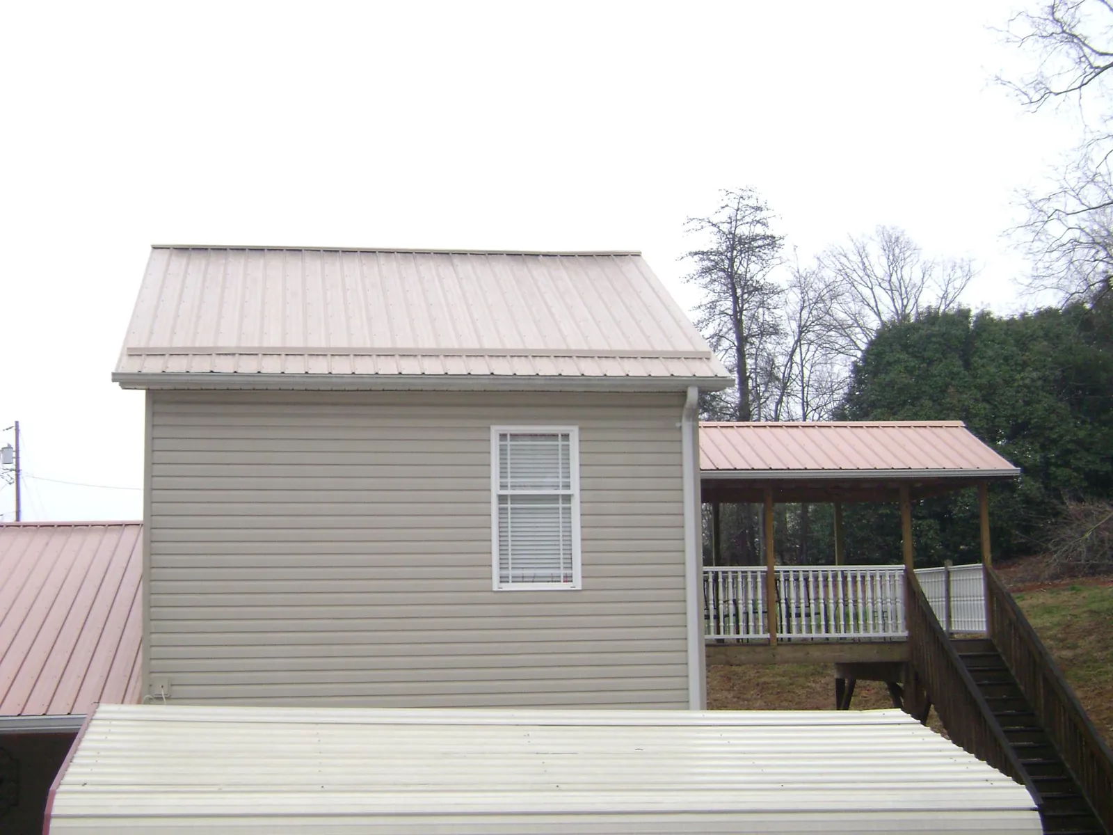 Tan metal roofs on a two story addition and attached porch, from a Roof Replacement job in Dungannon