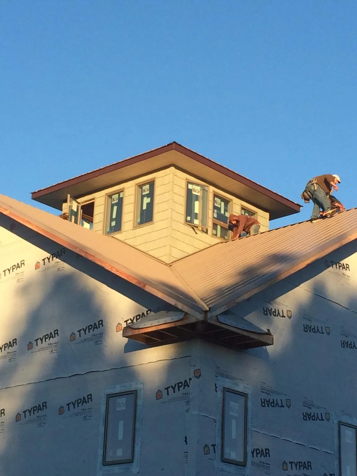 Roofers working around a rooftop cupola on a new metal roof at sunset — Roof Waterproofing in Dungannon by Roofing Brothers